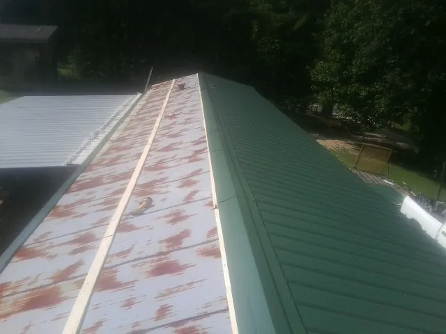 Old rusted panels beside newly installed green metal roofing — Wind Damage Roof Repair by Roofing Brothers in Greene