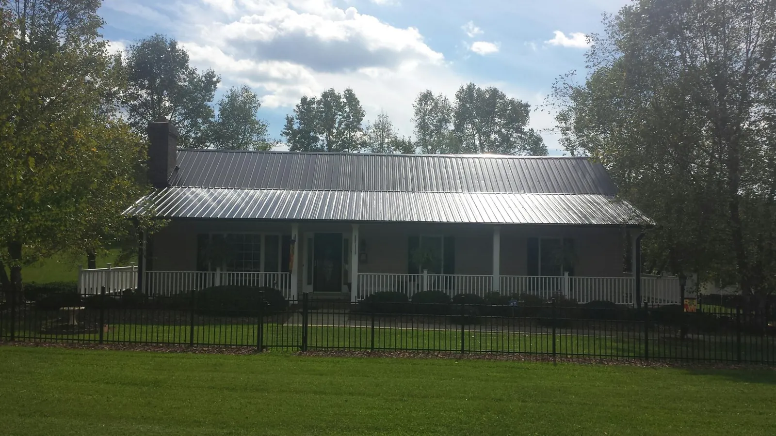 Gray metal roof on a brick ranch with a full width front porch — Gutter Guard Installation work by our crew in Greene
