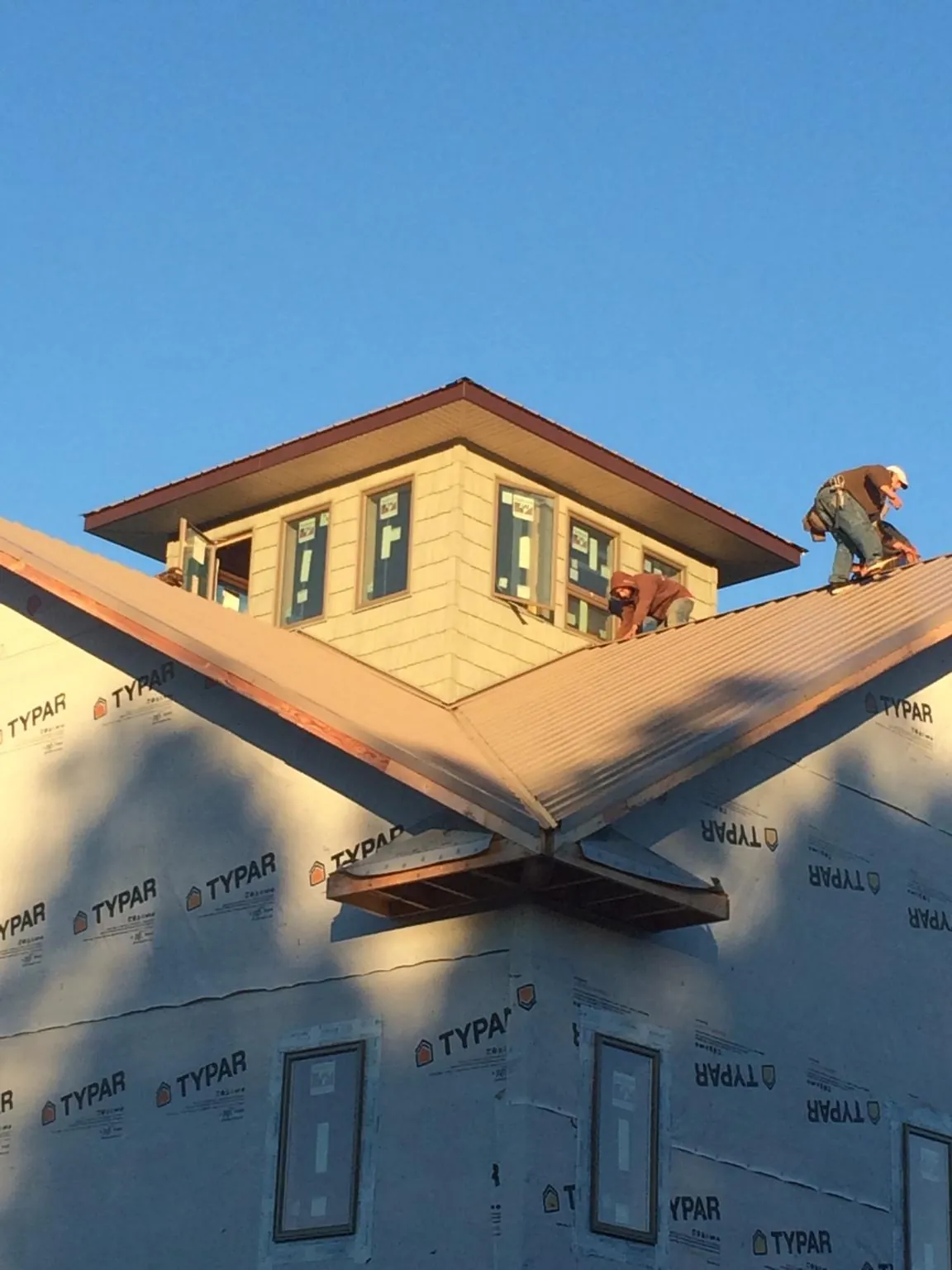 Roofers working around a rooftop cupola on a new metal roof at sunset — Roof Waterproofing in Greene by Roofing Brothers